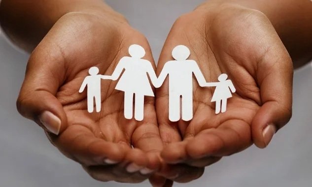 life insurance, love and charity concept – closeup of womans cupped hands showing paper man family
